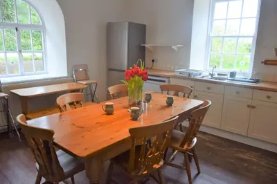 a kitchen with a wooden table with chairs and a large wooden table at The Stables in Carsethorn