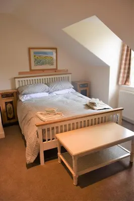 a bedroom with a large bed and a table at The Stables in Carsethorn