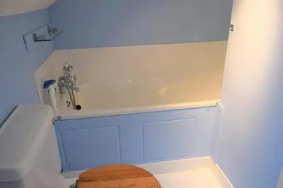 a bathroom with a white tub and a toilet at Coachmans Cottage in Carsethorn