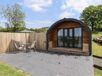 a wooden cabin with a table and chairs on a patio at Cleugh Lodge in Lockerbie