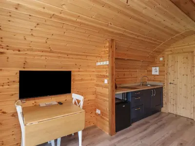 a kitchen with a desk and a tv in a wooden room at Cleugh Lodge in Lockerbie