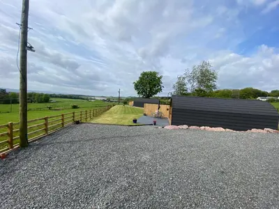 a barn with a fence next to a field at Dryfe Lodge in Lockerbie