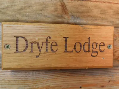 a wooden sign that reads dipride lodge on a wooden wall at Dryfe Lodge in Lockerbie