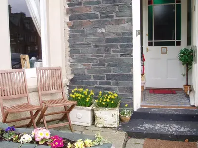 two chairs on the porch of a house with flowers at Herdwick Guest House in Keswick