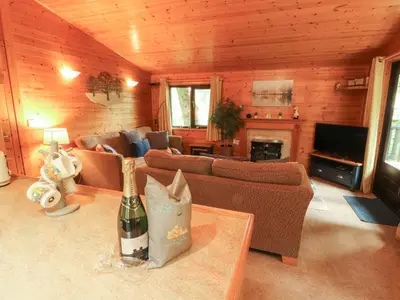 a living room with a couch and a table with a bottle of wine at Derwent Lodge in Keswick