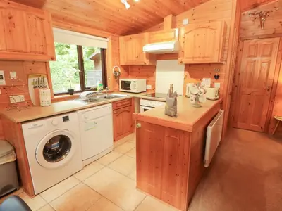 a kitchen with a washer and dryer in a cabin at Derwent Lodge in Keswick