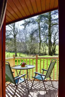 a patio with a table and chairs on a porch at Secluded Pine Lodge 2 in Wigton