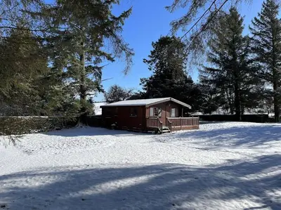 a small cabin in a snow covered yard at Secluded Pine Lodge 2 in Wigton
