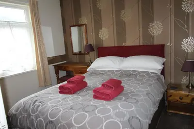 a bedroom with a bed with two red pillows on it at Skiddaw Grove in Keswick