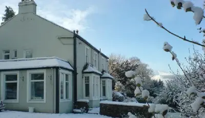 a white house with snow on the side of it at Skiddaw Grove in Keswick