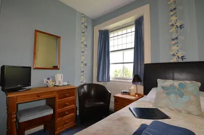 a bedroom with a bed and a desk and a television at Skiddaw Grove in Keswick