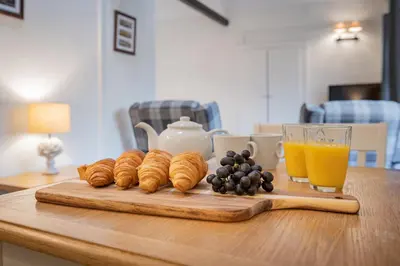 a table with a bunch of croissants and a glass of orange juice at Cottage 5 mews Studio in Keswick