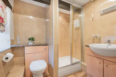 a bathroom with a shower and a toilet and a sink at Cottage 5 mews Studio in Keswick