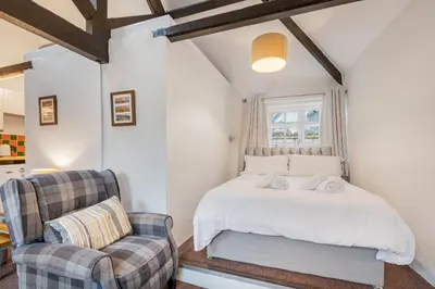 a bedroom with a white bed and a chair at Cottage 5 mews Studio in Keswick