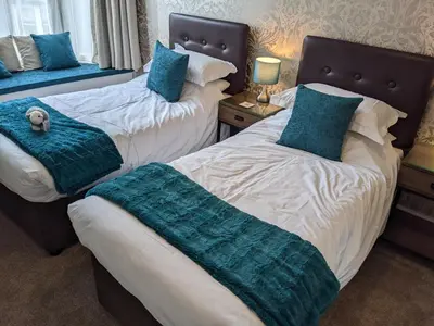 a bedroom with two beds with blue pillows at Avondale Guest House in Keswick
