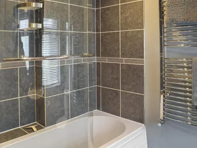 a bathroom with a tub and a glass shower at Winlocke Cottage in Leadhills