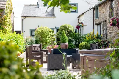 a garden with a table and chairs and flowers at Brae Fell Cottage, Sebergham, Nr Caldbeck dog friendly and hot tub in Sebergham