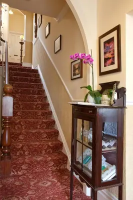 a hallway with stairs with a table and flowers at The Edwardene in Keswick