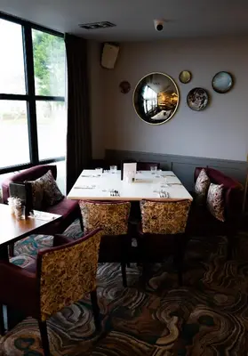 a dining room with two tables and a mirror at The Fenwick Hotel in Kilmarnock