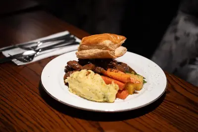 a plate with a sandwich and carrots on a table at The Fenwick Hotel in Kilmarnock