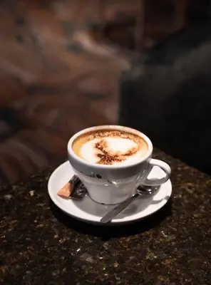 a cup of coffee on a plate on a table at The Fenwick Hotel in Kilmarnock