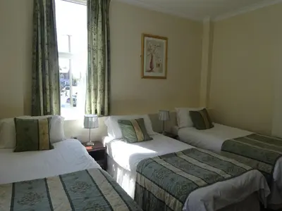 three beds in a room with a window at Waverley Hotel in Workington