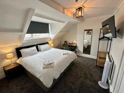 a bedroom with a bed with white sheets and a mirror at Waverley Hotel in Workington
