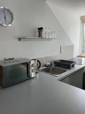 a kitchen with a sink and a clock on the wall at Luxury Studio Loft with Car Charging Point in Frizington