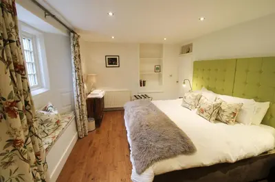 a bedroom with a large bed with a green headboard at Calley House, Hutton remote cottage with hot tub, 10 minutes to Ullswater in Penruddock