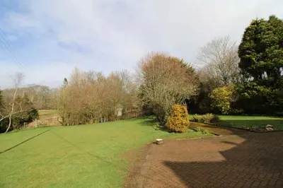 a large grassy yard with trees and a brick driveway at Calley House, Hutton remote cottage with hot tub, 10 minutes to Ullswater in Penruddock