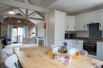 a kitchen with a wooden table and white cabinets at Cloven Stone, Nr Caldbeck ideal family accommodation with hot tub in Sebergham