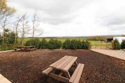a picnic table and picnic tables in a field at Cloven Stone, Nr Caldbeck ideal family accommodation with hot tub in Sebergham