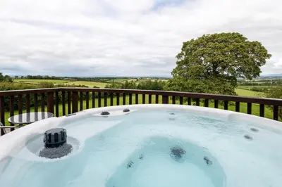 a jacuzzi tub on a deck with a view at Cloven Stone, Nr Caldbeck ideal family accommodation with hot tub in Sebergham