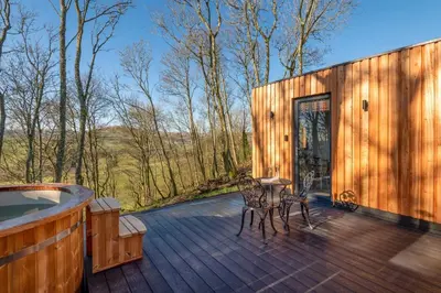 a wooden deck with a tub and a table and chairs at Daffodil, Penruddock Eco & dog friendly lodge with hot tub in Penruddock