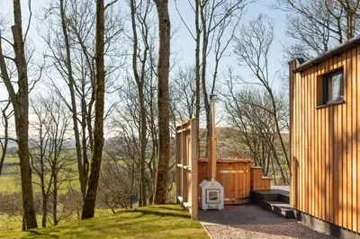 a wooden house in the woods with a door at Daffodil, Penruddock Eco & dog friendly lodge with hot tub in Penruddock
