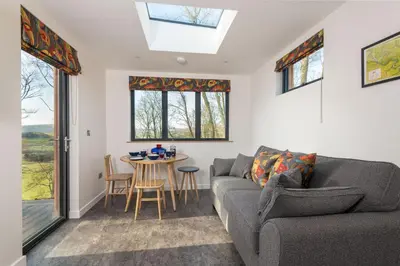 a living room with a couch and a table at Daffodil, Penruddock Eco & dog friendly lodge with hot tub in Penruddock