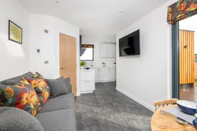 a living room with a couch and a kitchen at Daffodil, Penruddock Eco & dog friendly lodge with hot tub in Penruddock