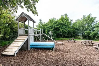 a playground with a blue slide and two benches at Fisher Gill, Sebergham, Close to Caldbeck Fells with hot tub in Sebergham