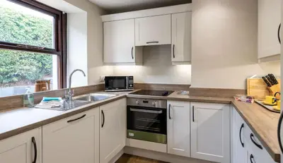 a kitchen with white cabinets and a sink and a window at Fisher Gill, Sebergham, Close to Caldbeck Fells with hot tub in Sebergham