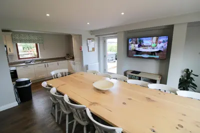 a dining room with a large wooden table and chairs at Great Calva, Sebergham, perfect for 2 families or friends with 3 dogs welcome and hot tub in Sebergham