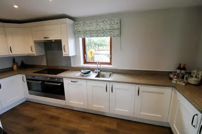 a kitchen with white cabinets and a sink and a window at Great Calva, Sebergham, perfect for 2 families or friends with 3 dogs welcome and hot tub in Sebergham