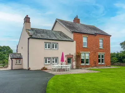 a large brick house with tables and chairs in the yard at High House, Southwaite in a rural setting with countryside views, garden with BBQ & hot tub in Southwaite