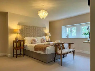 a bedroom with a bed and a chair and a chandelier at High House, Southwaite in a rural setting with countryside views, garden with BBQ & hot tub in Southwaite