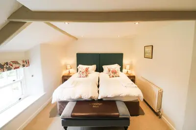 a bedroom with a bed with a green headboard at Red Squirrel Cottage, Hutton luxurious cottage in a rural setting 10 minutes to Ullswater 15 minutes to Keswick in Penruddock