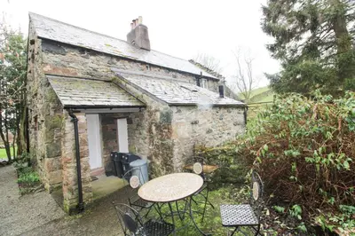a table and chairs in front of a stone building at Red Squirrel Cottage, Hutton luxurious cottage in a rural setting 10 minutes to Ullswater 15 minutes to Keswick in Penruddock