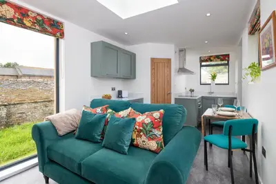 a living room with a green couch and a table at Ruecroft, Penruddock an Eco & dog friendly lodge with a hot tub, 10 minutes from Lake Ullswater in Penruddock