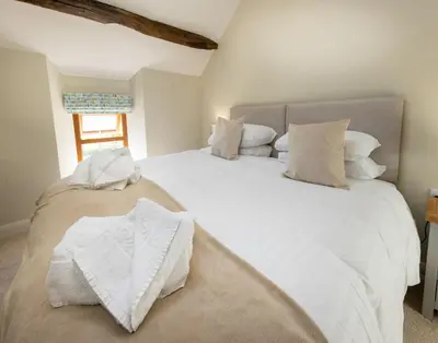 a bedroom with two beds with white sheets and a window at The Farmhouse, Sebergham, spacious family or group accommodation in a rural setting close to Caldbeck in Sebergham