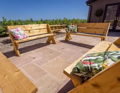 two benches with pillows sitting on a patio at The Farmhouse, Sebergham, spacious family or group accommodation in a rural setting close to Caldbeck in Sebergham
