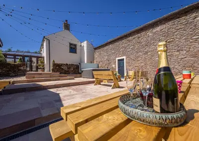 a bottle of wine sitting on a wooden table with wine glasses at The Farmhouse, Sebergham, spacious family or group accommodation in a rural setting close to Caldbeck in Sebergham