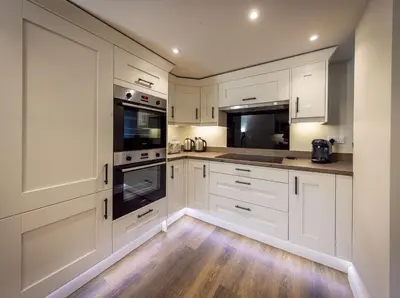 a white kitchen with white cabinets and wooden floors at The Farmhouse, Sebergham, spacious family or group accommodation in a rural setting close to Caldbeck in Sebergham